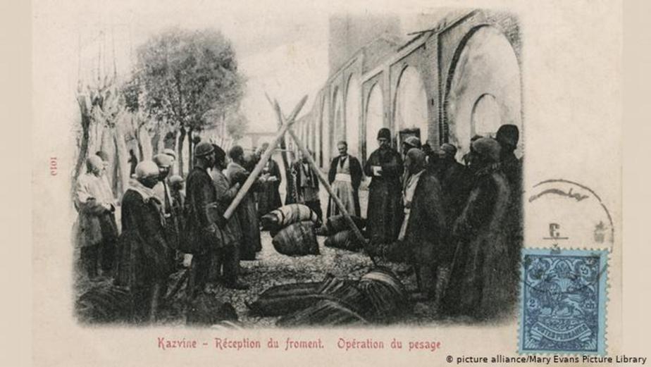 بازار قزوین. مردانی در حال وزن کردن پارچه. تاریخ عکس: ۱۹۰۳ میلادی