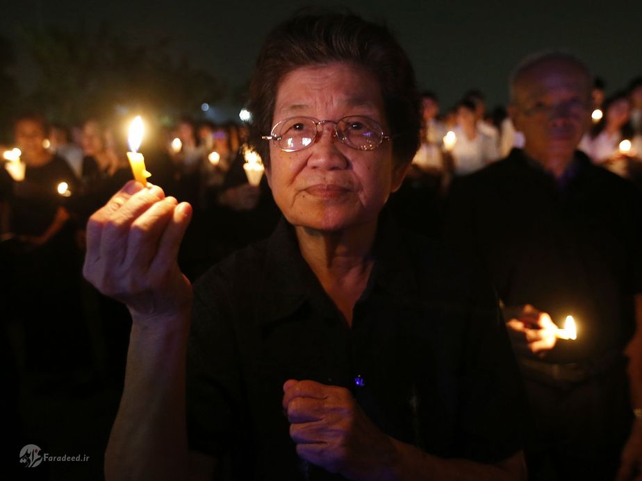 تایلند| زنی که با روشن کردن شمعی در بانکوک، مشغول به عزاداری برای سالمرگ پادشاه بومیپول آدولیاده است. بومیپول، سال گذشته و پس از هفت دهه سلطنت در سن ۸۸ سالگی در گذشت