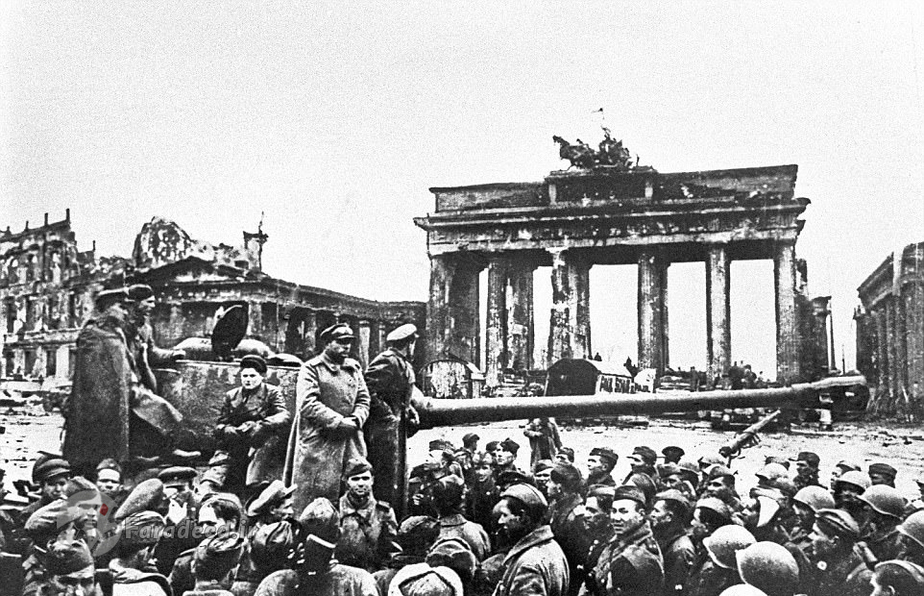 نیروهای شوروی در نزدیکی دروازه براندنبورگ برلین – این عکس نیز مشهور شد. یوگنی در سن 18 سالگی به خبرگزاری تاس شوروی پیوست در سال 1941 میلادی برای عکاسی عازم جنگ شد